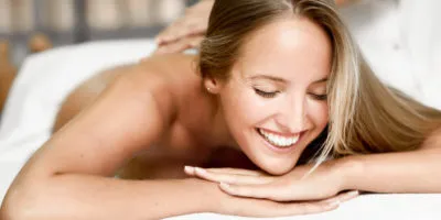 Young blond woman having massage in the spa salon. Massage and body care. Body massage treatment. Smiling female.