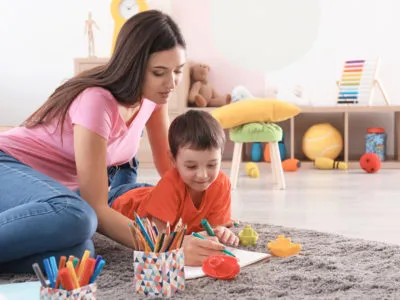 Little boy drawing with nanny at home