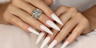 Long light manicure with jewelry on a woman's hand.